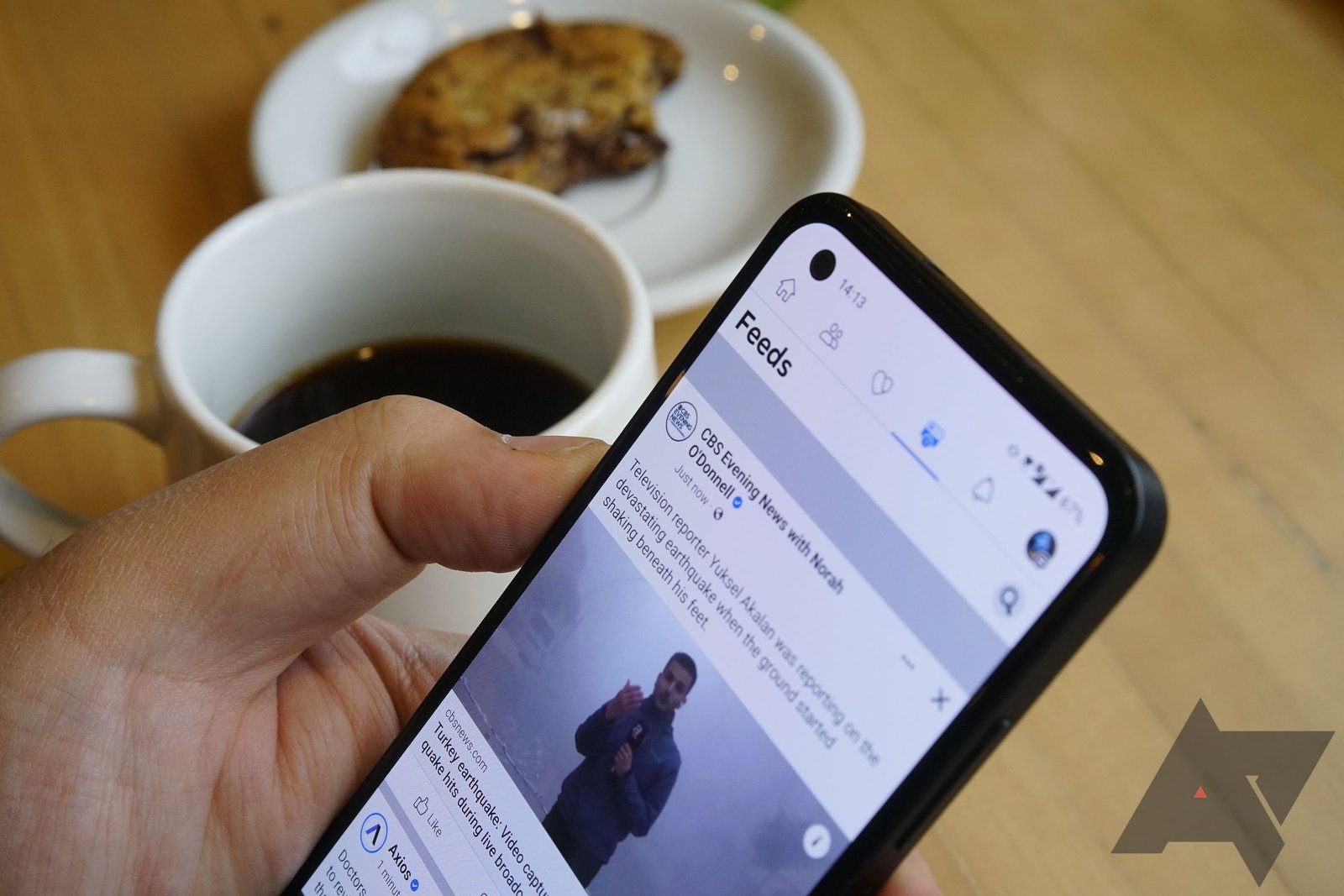 The Facebook app on a smartphone with coffee and a cookies in the background